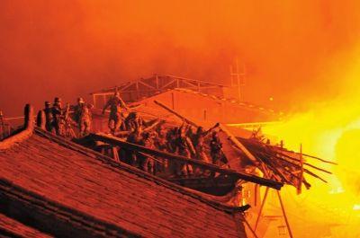 昨天凌晨,救火人员在拆除火场周边建筑,设立隔离带。新华社发