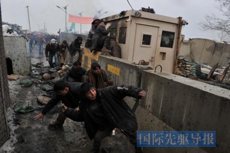 2月21日,阿富汗民众聚集在巴格拉姆空军基地外,抗议北约联军亵渎古兰经的行为。图为阿富汗青年在抗议活动中向美军士兵扔石块。新华/法新 2月21日,阿富汗民众聚集在巴格拉姆空军基地外,抗议北约联军亵渎古兰经的行为。图为阿富汗青年在抗议活动中向美军士兵扔石块。新华/法新