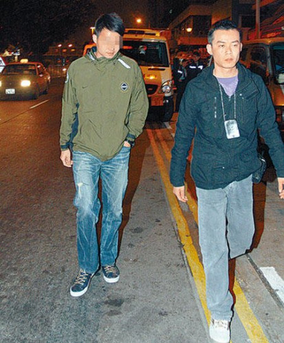涉嫌与伤人案有关其中一名休班反黑组探员(左),由警员带走协助调查。 涉嫌与伤人案有关其中一名休班反黑组探员(左),由警员带走协助调查。