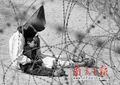 9年间,伊战共造成大约4500名美军士兵死亡,超过10万伊拉克人丧生。这是2003年3月31日,在伊拉克纳杰夫附近的战俘营内,一名头被面罩蒙住的伊拉克男子在安慰自己4岁的儿子。 新华社发 9年间,伊战共造成大约4500名美军士兵死亡,超过10万伊拉克人丧生。这是2003年3月31日,在伊拉克纳杰夫附近的战俘营内,一名头被面罩蒙住的伊拉克男子在安慰自己4岁的儿子。 新华社发