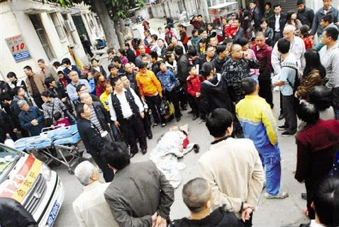 卖菜的摊贩杨阿伯躺在海天小区门口,很多群众在围观 卖菜的摊贩杨阿伯躺在海天小区门口,很多群众在围观