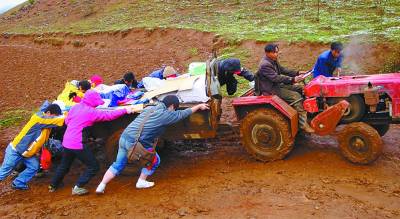 义工们合力推动拖拉机,孩子们的药品、书本常常就这样运抵山村。 义工们合力推动拖拉机,孩子们的药品、书本常常就这样运抵山村。