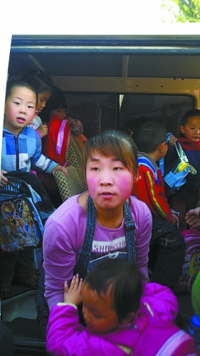 跟车老师抱起一个孩子下车,背后的车厢内仍挤满了孩子。 跟车老师抱起一个孩子下车,背后的车厢内仍挤满了孩子。