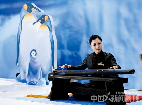 5月12日,2012韩国丽水世博会中国馆的演员正在演奏古琴,左侧是“企鹅一家”的布景。图 / 中新 侯宇 5月12日,2012韩国丽水世博会中国馆的演员正在演奏古琴,左侧是“企鹅一家”的布景。图 / 中新 侯宇