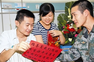 看着两面都带有战士们亲笔签名的慰问信,王志攀(左一)开心地笑了。王伟红摄 看着两面都带有战士们亲笔签名的慰问信,王志攀(左一)开心地笑了。王伟红摄