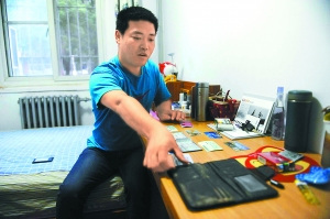 刘刚回到家，在写字台上晾晒被水浸透了的钱包。景一鸣 摄