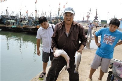 7月30日,山东胶南市积米崖码头,一市民钓到的美国红鱼。 刘洪雷 摄 7月30日,山东胶南市积米崖码头,一市民钓到的美国红鱼。 刘洪雷 摄