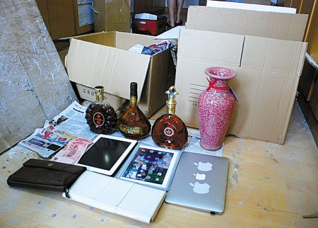 张某偷来的洋酒、IPAD、古董等,后面还有两纸箱赃物。(沈孙晖 摄) 张某偷来的洋酒、IPAD、古董等,后面还有两纸箱赃物。(沈孙晖 摄)