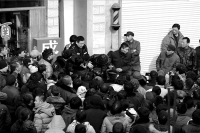 僵持近两小时后,嫌疑人被警方救下,引来周围大量群众围观。 本报记者徐晓帆摄 僵持近两小时后,嫌疑人被警方救下,引来周围大量群众围观。 本报记者徐晓帆摄