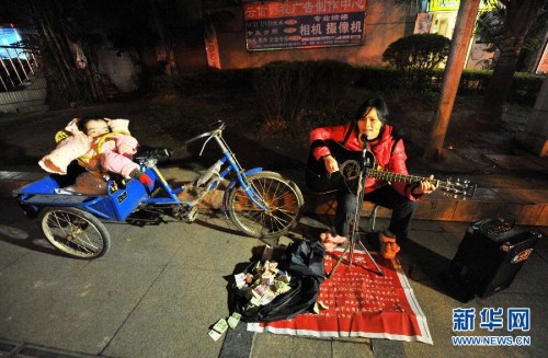 图为“卖唱妈妈”华青在广西柳州市解放北路街头唱歌(1月27日摄)。 图为“卖唱妈妈”华青在广西柳州市解放北路街头唱歌(1月27日摄)。