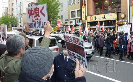 3月31日,反在日朝鲜半岛人的团体在东京新大久保游行(图片远景),高喊过激口号。市民则在路对面高举“让我们和睦相处”等标语牌对此表示抗议。(图片来源:日本共同社) 3月31日,反在日朝鲜半岛人的团体在东京新大久保游行(图片远景),高喊过激口号。市民则在路对面高举“让我们和睦相处”等标语牌对此表示抗议。(图片来源:日本共同社)