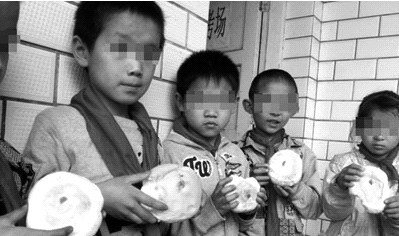 雨汪小学的小学生手里拿着领到的面包。 雨汪小学的小学生手里拿着领到的面包。