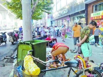 满地臭烘烘的垃圾又多又重,用扫帚根本扫不动,环卫大叔弯身手捧垃圾惹人心疼。