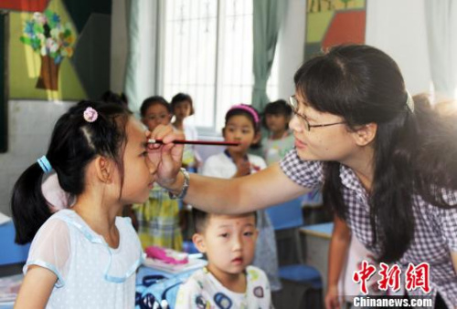 图为,武汉梨园小学一年级老师正在给学生点朱砂。 徐金波 摄 图为,武汉梨园小学一年级老师正在给学生点朱砂。 徐金波 摄