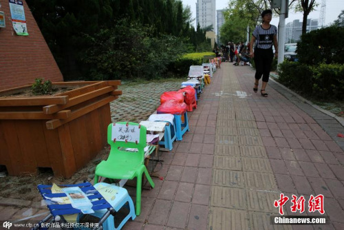 资料图:2015年8月,山东省东营市,为孩子上学报名,家长提前一两天在中心城区的部分小学门口,用马扎“安营扎寨” ,排起长队。 图片来源:CFP视觉中国 资料图:2015年8月,山东省东营市,为孩子上学报名,家长提前一两天在中心城区的部分小学门口,用马扎“安营扎寨” ,排起长队。 图片来源:CFP视觉中国