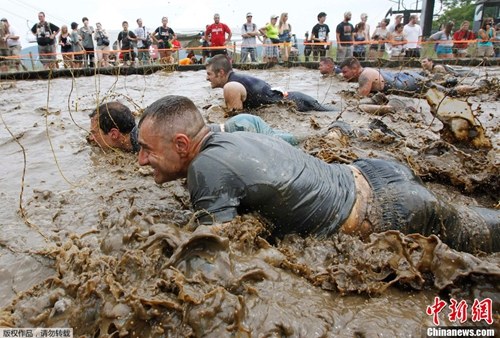 美国佛蒙特州举行硬汉挑战赛。挑战赛是一个9英里的耐力项目,包括穿越泥潭、火堆和隧道等障碍。图为参赛选手在泥水中行进。 美国佛蒙特州举行硬汉挑战赛。挑战赛是一个9英里的耐力项目,包括穿越泥潭、火堆和隧道等障碍。图为参赛选手在泥水中行进。