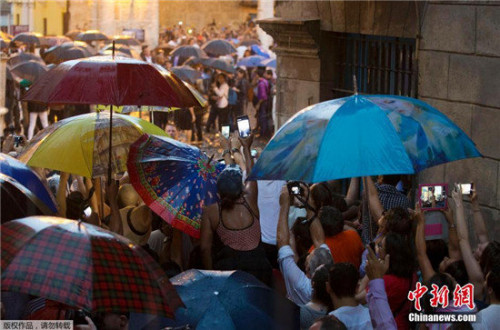 古巴民众冒雨夹道等待奥巴马一行经过。 古巴民众冒雨夹道等待奥巴马一行经过。