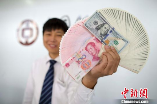 资料图:山西太原银行工作人员正在展示人民币、美元。 张云 摄 资料图:山西太原银行工作人员正在展示人民币、美元。 张云 摄
