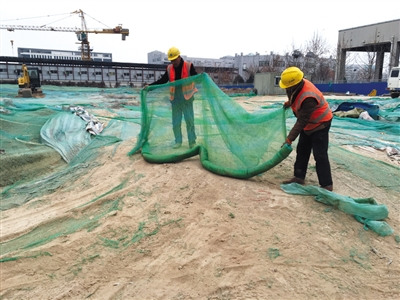 工人正在加盖防尘网。新京报记者 朱自洁 摄 工人正在加盖防尘网。新京报记者 朱自洁 摄