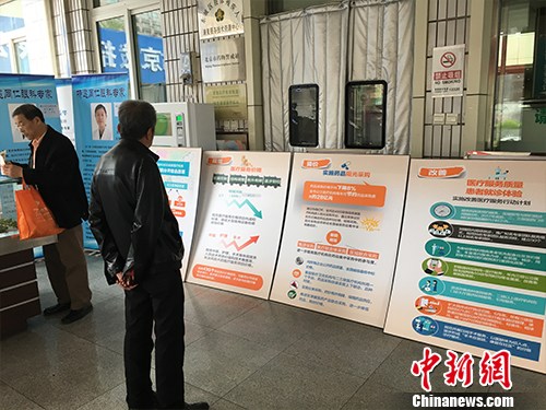 北京普仁医院外，有人在看医改宣传板。