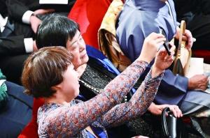 12月10日,莫言的夫人杜勤兰(上)、女儿管笑笑在颁奖现场拍照。 新华社发