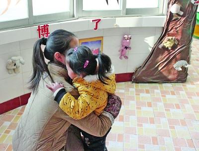 江都商贸幼儿园一位老师在拥抱该园的孩子。因为涉及收费,作为该园精品教育的一个项目,老师的拥抱行为也被质疑。 董鑫 摄