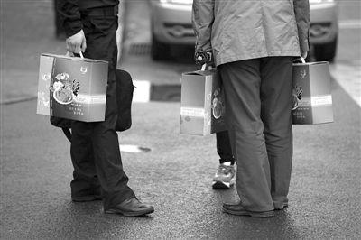 昨日,晚高峰,CBD几名上班族手提中秋节礼盒,站在路边。新京报记者 侯少卿 摄