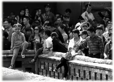 故宫,很多家长不顾工作人员劝阻,让孩子翻过墙头照相。京华时报记者 王海欣 摄