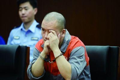 开庭时,王洪山一直用手将自己的脸挡住,不时从指缝里打量人 摄/法制晚报记者 刘畅