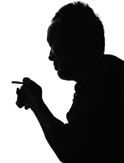 王坤亮用他残疾的左手燃起一支烟,7年前,他的儿子用刀砍在了他这只已经残疾的手臂上 摄/法制晚报记者 刘畅