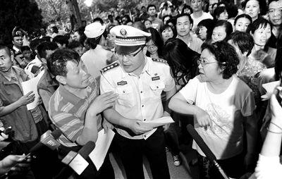 昨天晚上,丰台区城管队员在公园向广场舞大妈发放高考期间暂停跳舞或调低音量的倡议书摄影/本报记者 袁艺