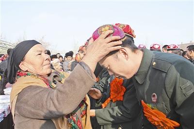 新疆村民为解放军退伍老兵戴小花帽送馕饼图