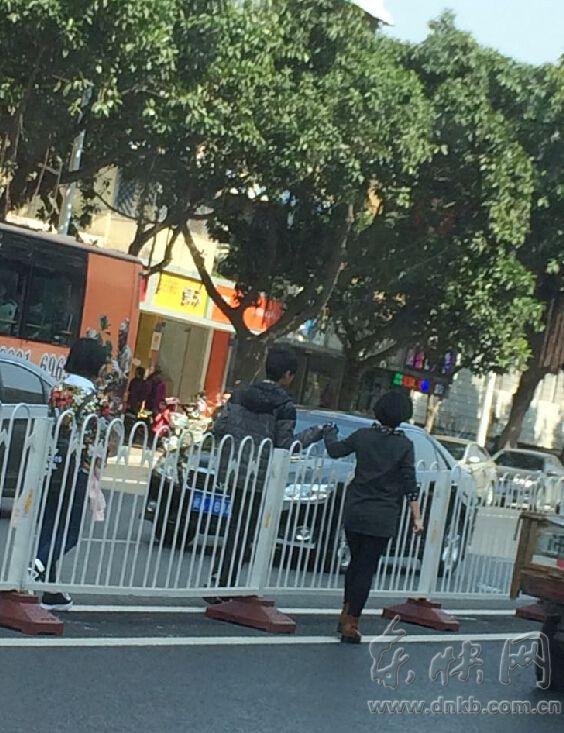 榕一年轻情侣当街秀恩爱 隔着护栏牵手走路中央