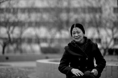 黄兴的母亲坐在小区内的石凳上哭泣。