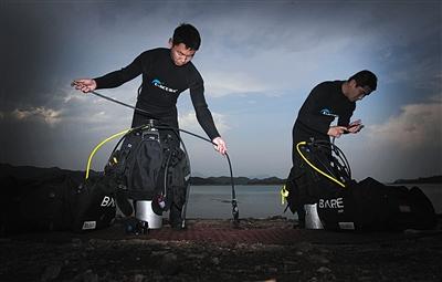 6月5日,两名潜水员正在岸边整理潜水设备。