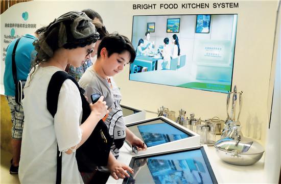 外国参观者在“光明智能厨房系统”展项处互动。