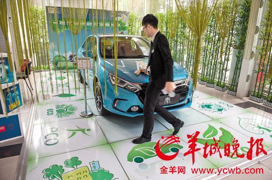 汽车4S店里的新能源汽车展位完全用绿色调装潢吸引顾客