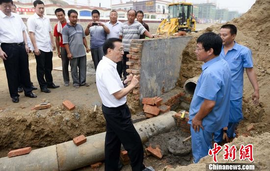 李克强沿泥坡下管沟细察雨水管线