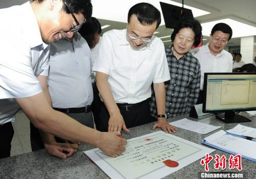 李克强与行政审批人员共同为新营业执照盖章
