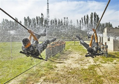 新疆阿克苏军分区官兵高压水枪喷射下练攀爬绳索