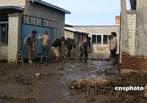 图洪水过后沙兰镇居民清理门前淤泥