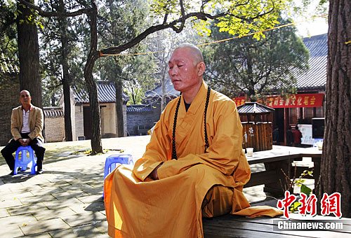 中华第一武僧",会善寺寺院住持释延武盘膝坐于一棵果树下的长条凳上练