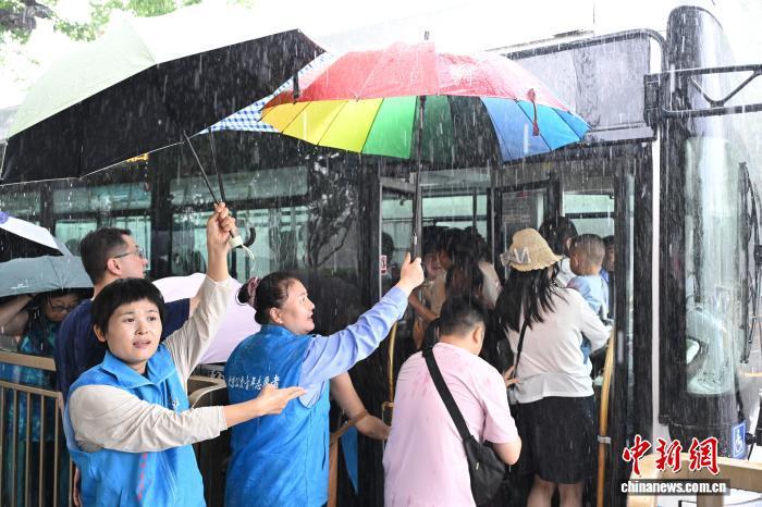 端午遇雨，北京公交青年志愿者为乘客撑伞避雨