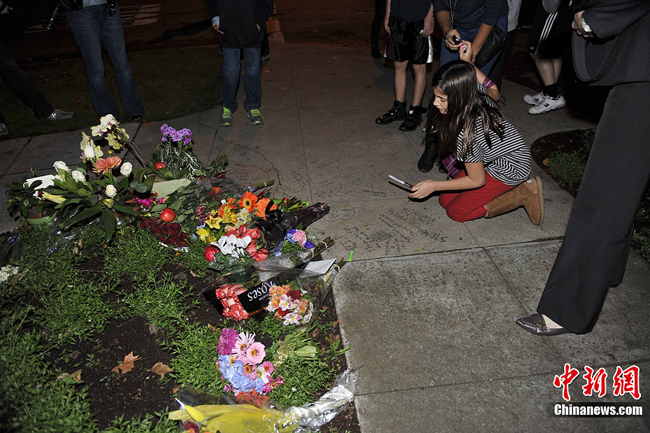 图为乔布斯家院外靠马路的街角上,一个美国女孩在悼念.