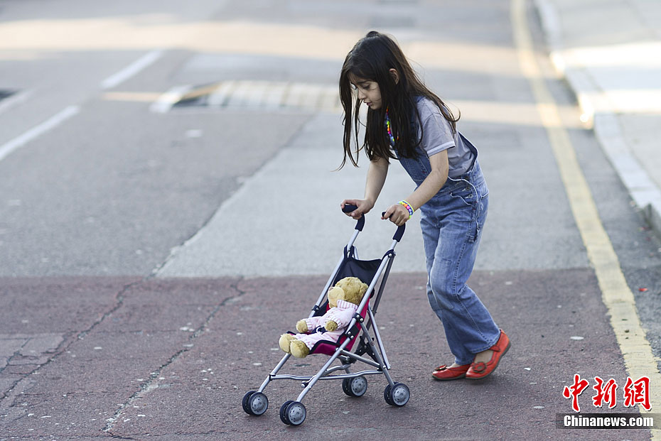 伦敦女孩用婴儿车推洋娃娃过马路