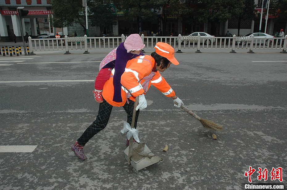 省郴州市安仁县七一西街上,一位一手提撮斗,一手拿扫帚的老奶奶清洁工