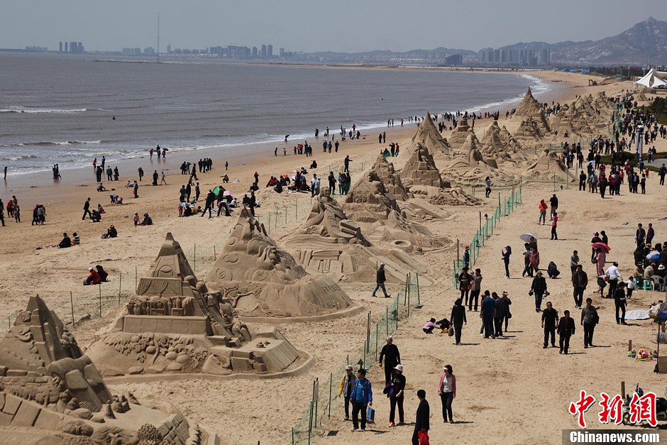 4月29日,山东省文登市南海公园的海滩上,众多游人在观看沙雕艺术展.