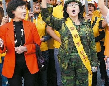 头戴钢盔,身穿迷彩军装,在亲民党不分区"立委"参选人陈秀霞陪同下